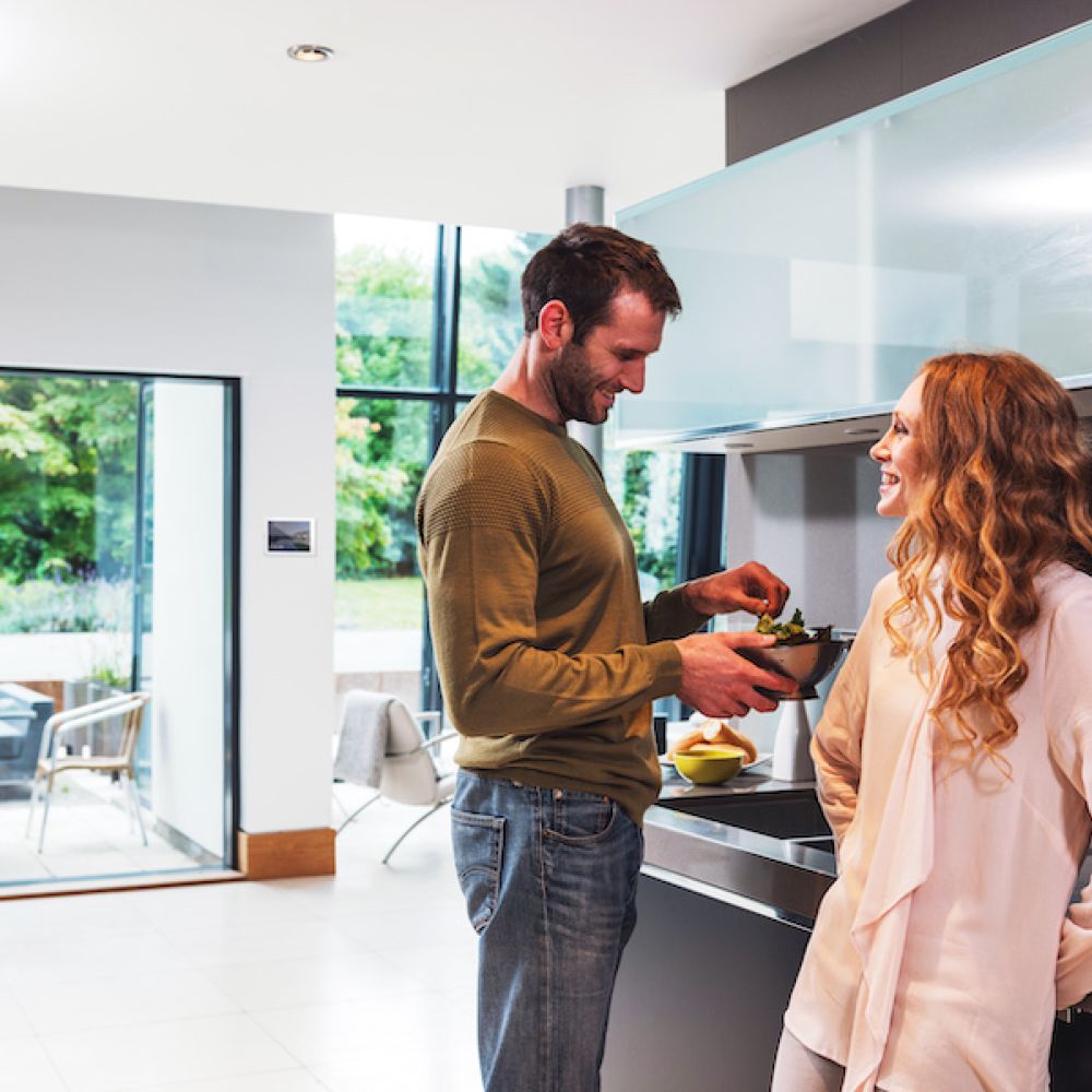 <span class="uk-h4">Control4 music interface on a TV mounted above a living room fireplace.</span>