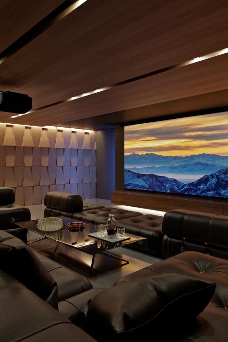 Luxurious home theater with wood-paneled walls and a scenic mountain sunset on the screen.