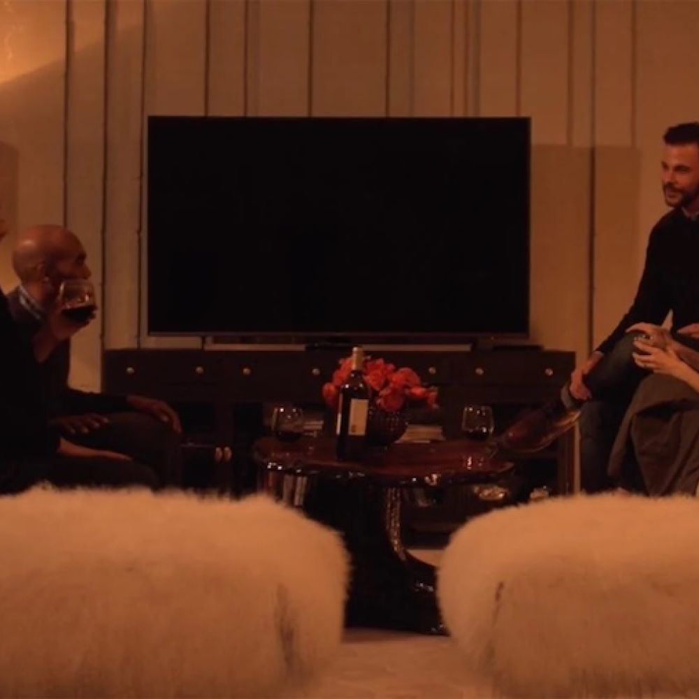 <span class="uk-h4">A group of people converse in a dimly lit room during cocktail hour.</span>