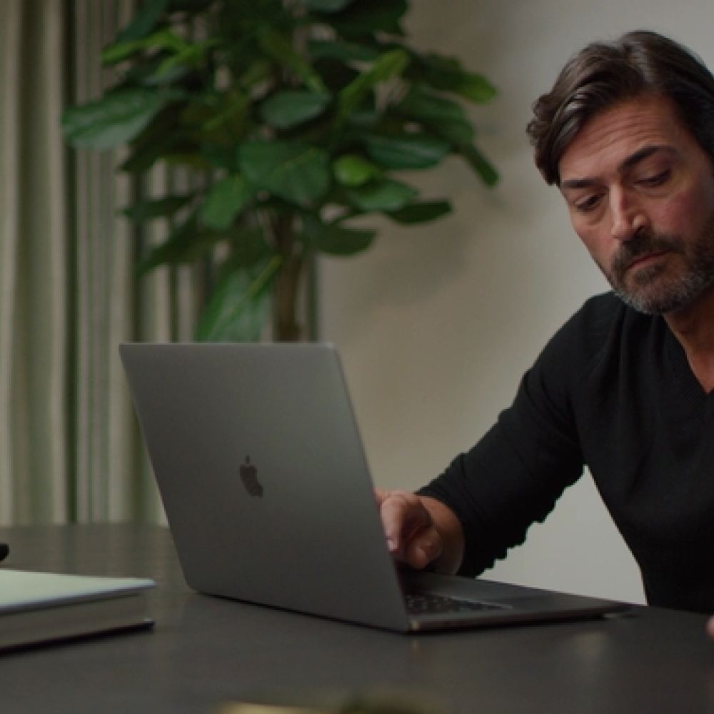 <span class="uk-h4">Man sits at a desk while using a laptop.</span>