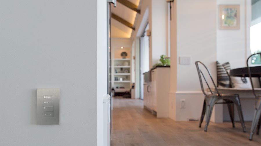 A bright living space with a smart wall control panel and a view of a cozy dining area.