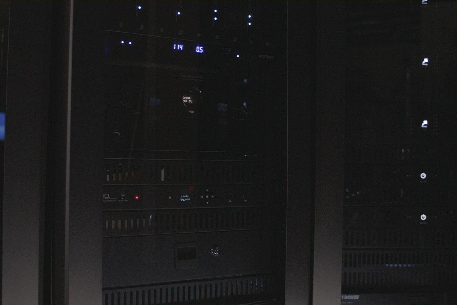 Close-up of a sleek AV rack with various devices and illuminated controls.