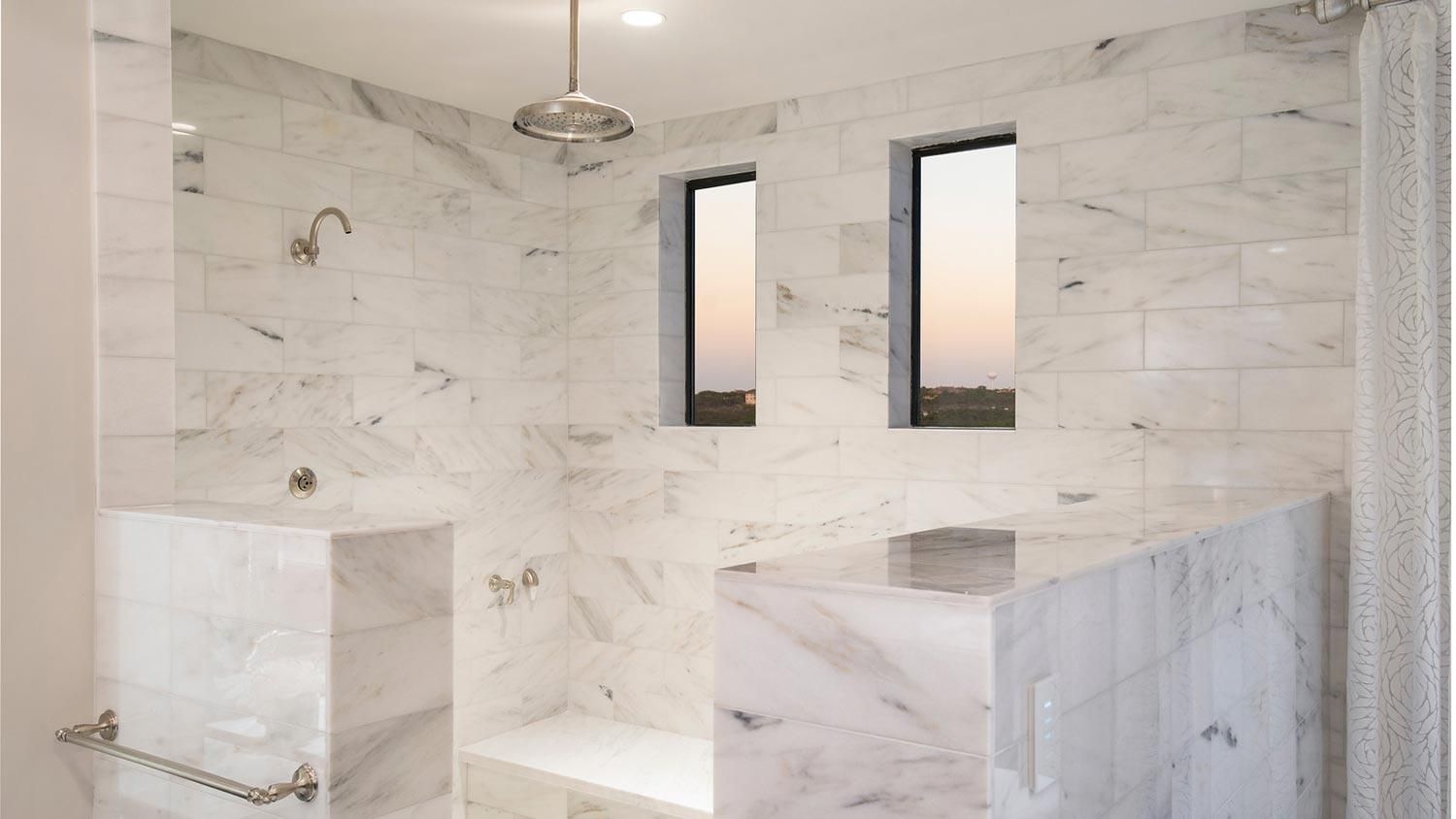 Luxurious bathroom featuring a large shower area with marble walls and multiple windows.