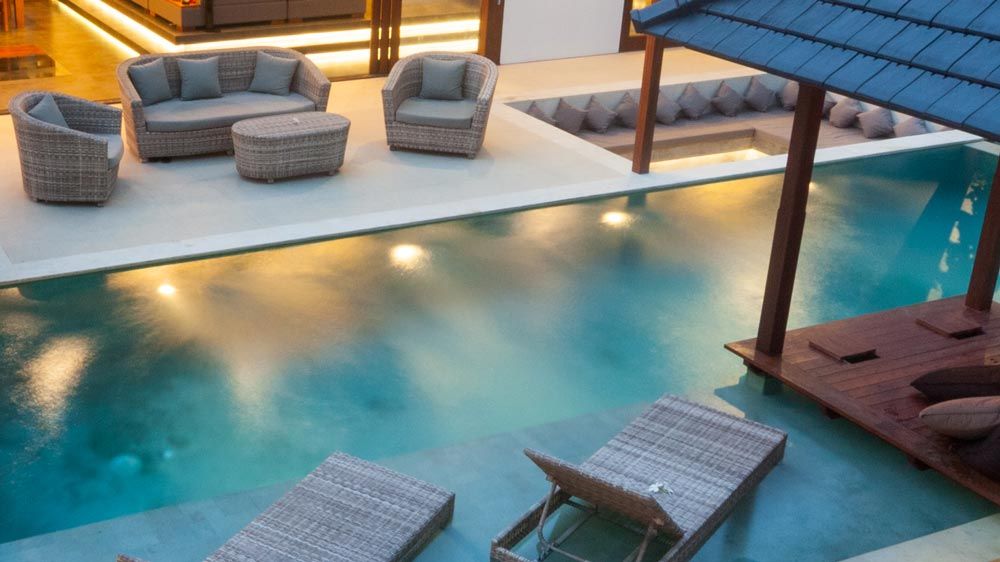 Evening view of a swimming pool with underwater lighting and cozy outdoor seating.