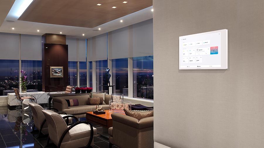 A luxurious living room with a wall-mounted smart home panel overlooking a cityscape.