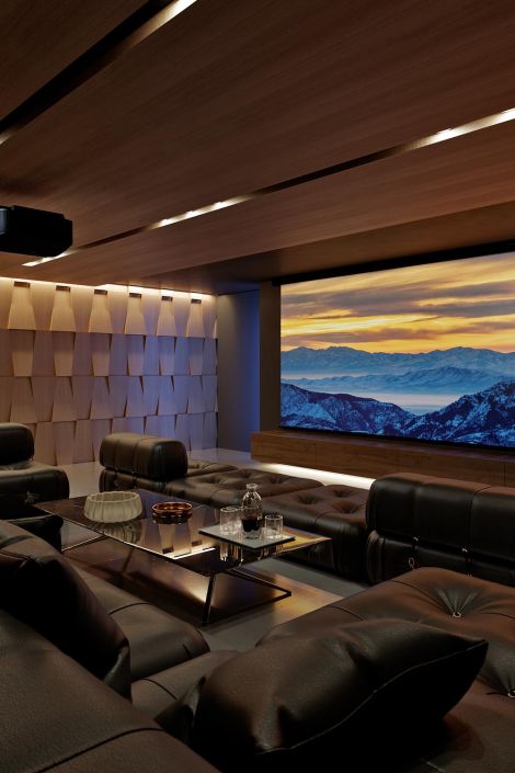 Luxurious home theater with wood-paneled walls and a scenic mountain sunset on the screen.