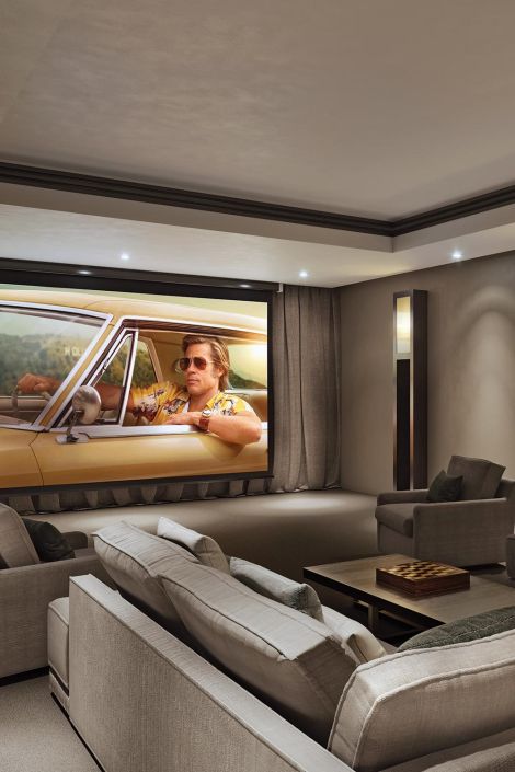 Elegant home cinema with neutral tones and a classic film playing on the projector screen.