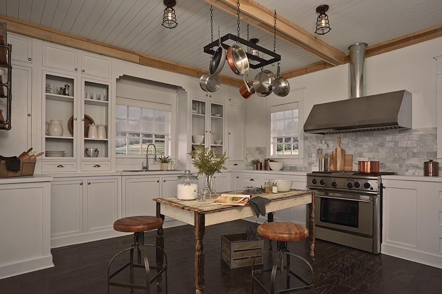 Farmhouse-style kitchen with exposed wood beams, hanging pots, and vintage-inspired fixtures.