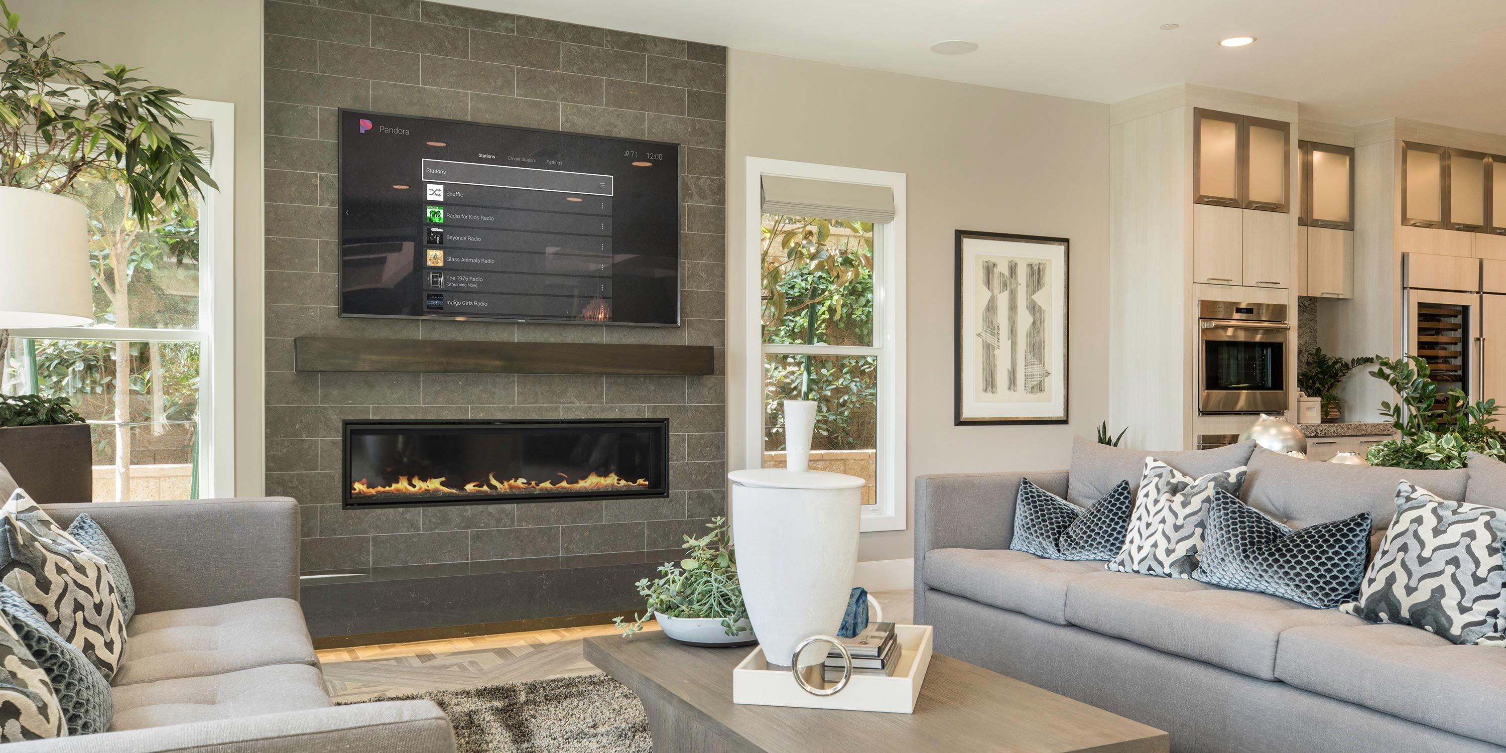 Cozy family room with a fireplace, comfortable sofas, and a large window view of greenery.