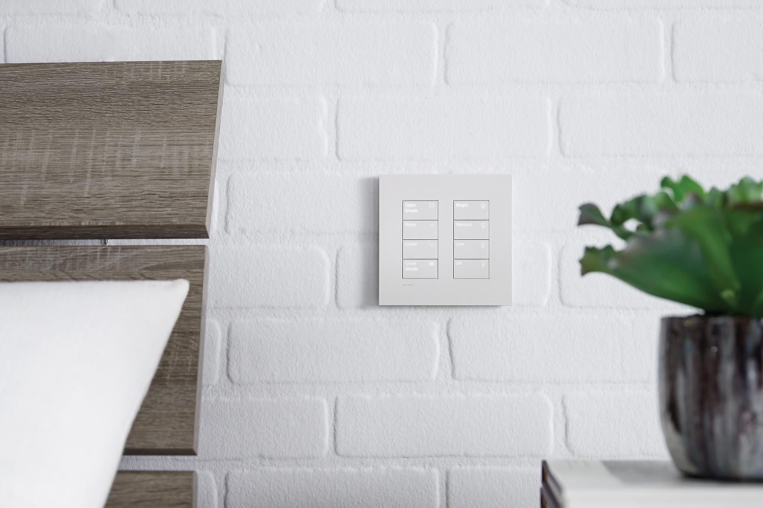 Minimalist bedroom corner featuring a smart lighting control panel and decor on a nightstand.