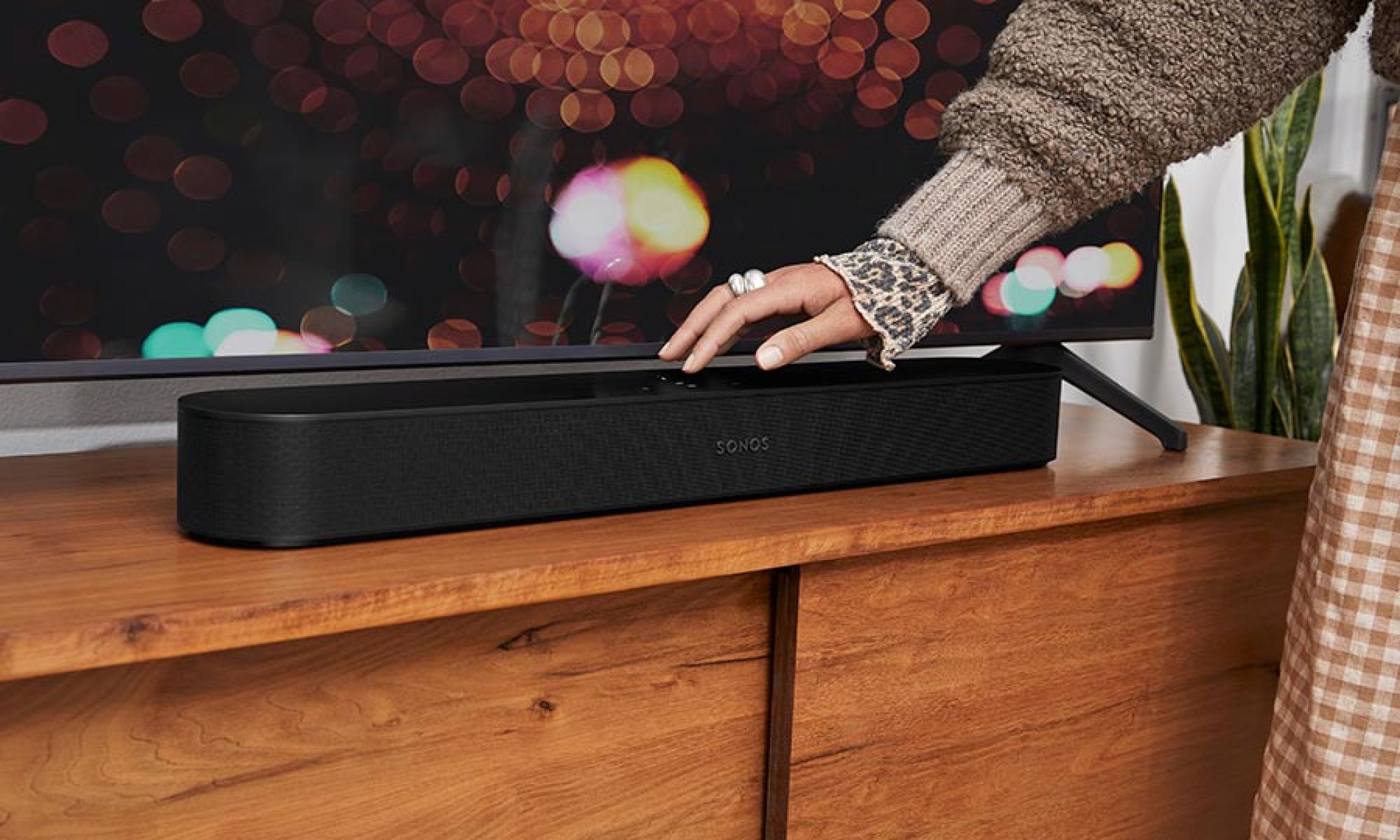 A compact soundbar placed on a wooden media console, blending seamlessly with the decor.